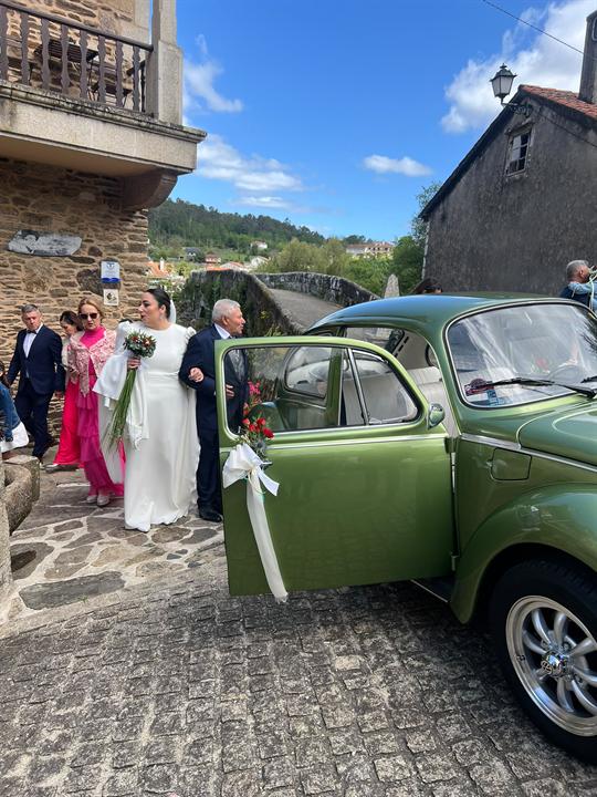 Novios saliendo hacia el escarabajo verde decorado con lazos blancos