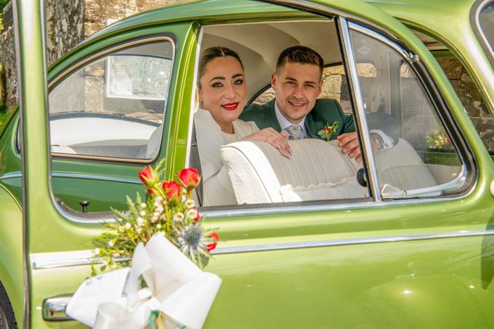 Novios en el coche clásico decorado con flores