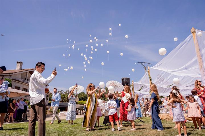 Invitados soltando globos blancos en el jardín
